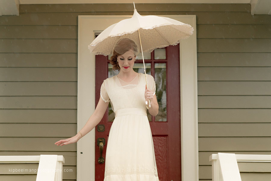 A bride departs her getting ready location and descends steps in her unique family heirloom wedding gown holding a vintage parasol from Bella Umbrella en route to her first look for her Golden Gardens Bathhouse wedding