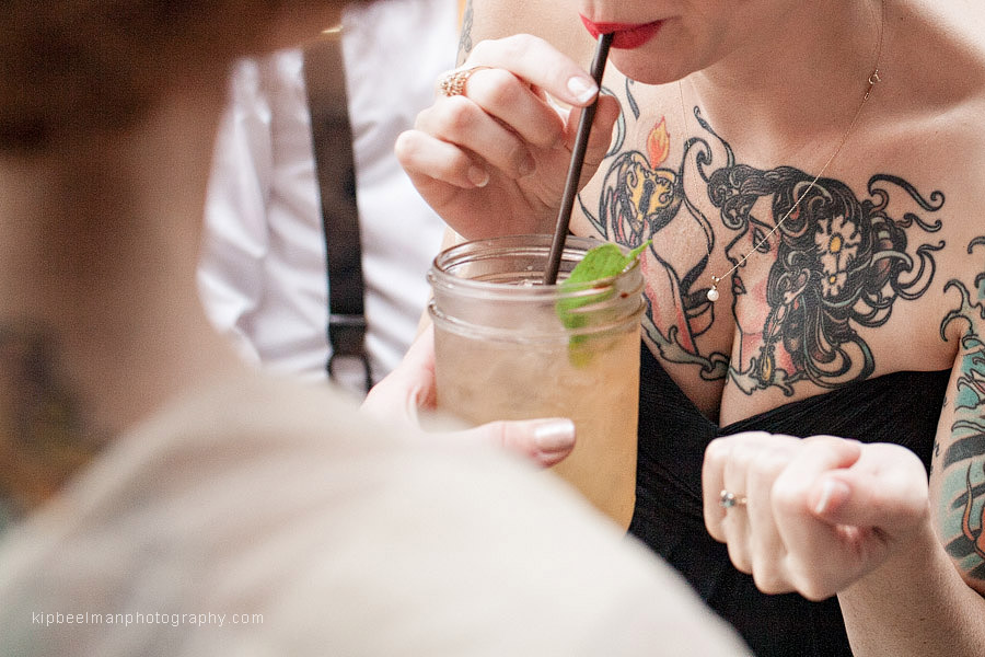 The maid of honor for a Golden Gardens Bathhouse wedding sips a mojito at King's Hardware in Ballard while her elaborate chest tattoo is highlighted