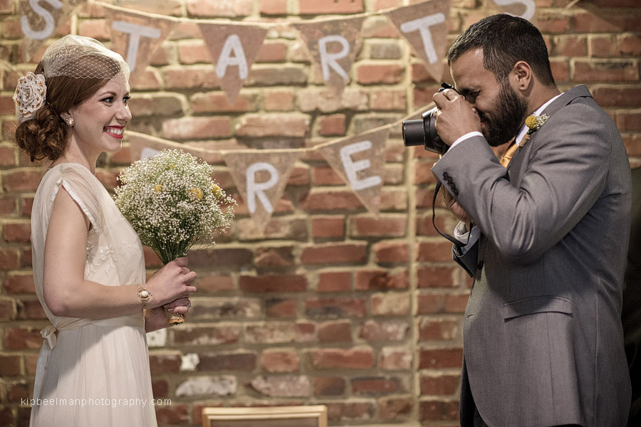 A groom takes a time out from his Golden Gardens Bathhouse wedding ceremony to snap a few instant camera photos of his bride