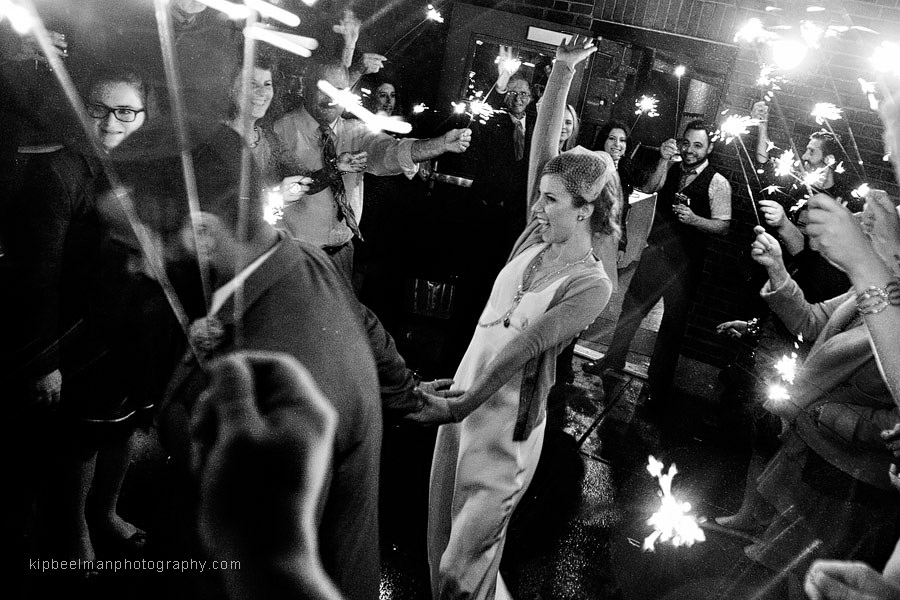 A groom tows his bride during their Golden Gardens Bathhouse wedding sparkler send off in the rain