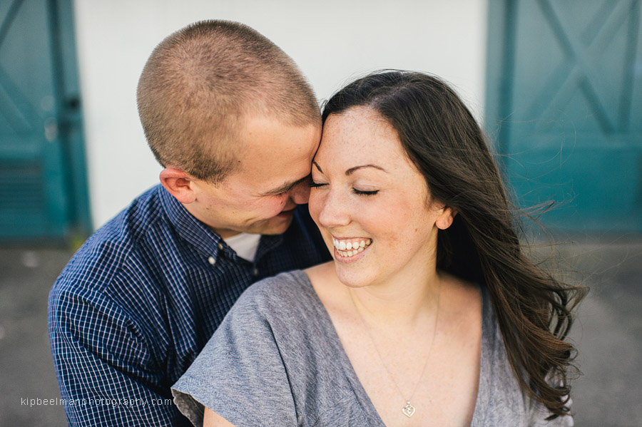 A couple snuggle in front of a net shed during their Fishermens Terminal engagement session